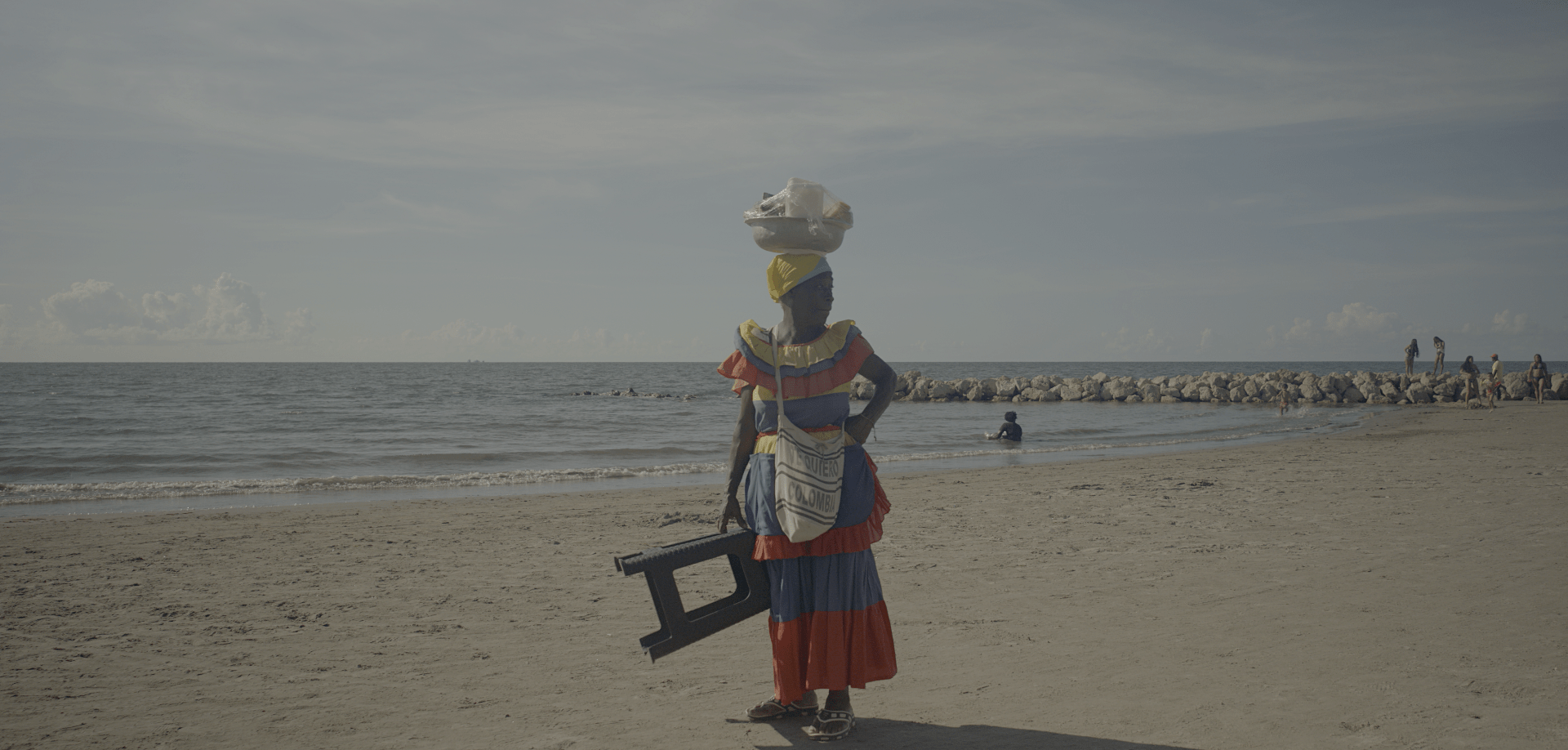 Nicolasa, an elder palenquera, looks away, standing on a beach in Cartagena, Colombia.